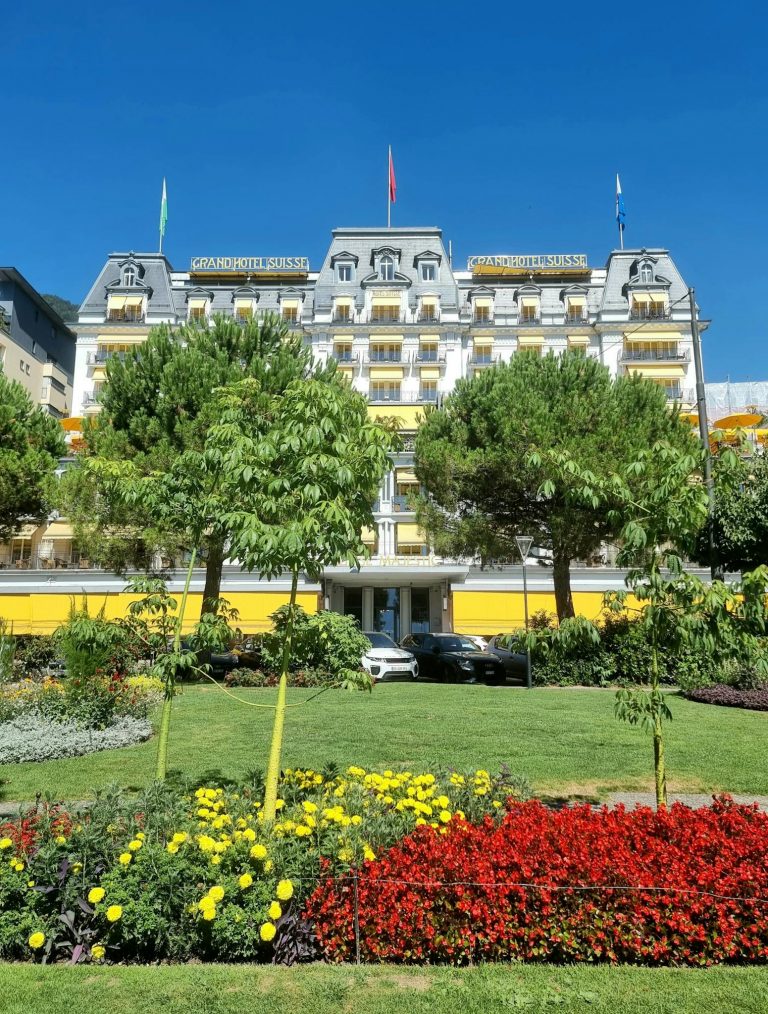 Captivating view of Grand Hotel Suisse Majestic with vibrant garden in Montreux, Switzerland.
